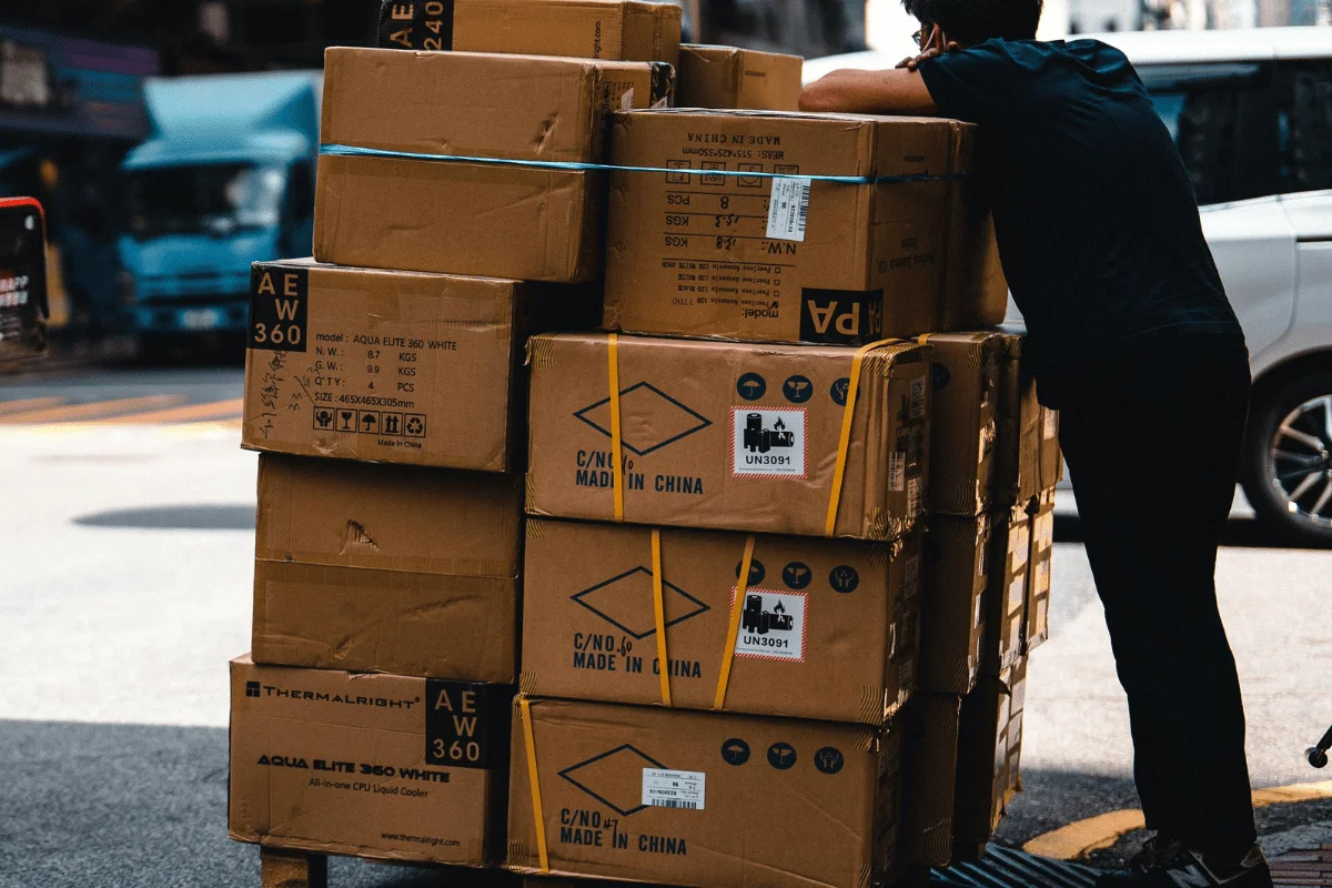 Person leaning on a stack of cardboard boxes on the street.