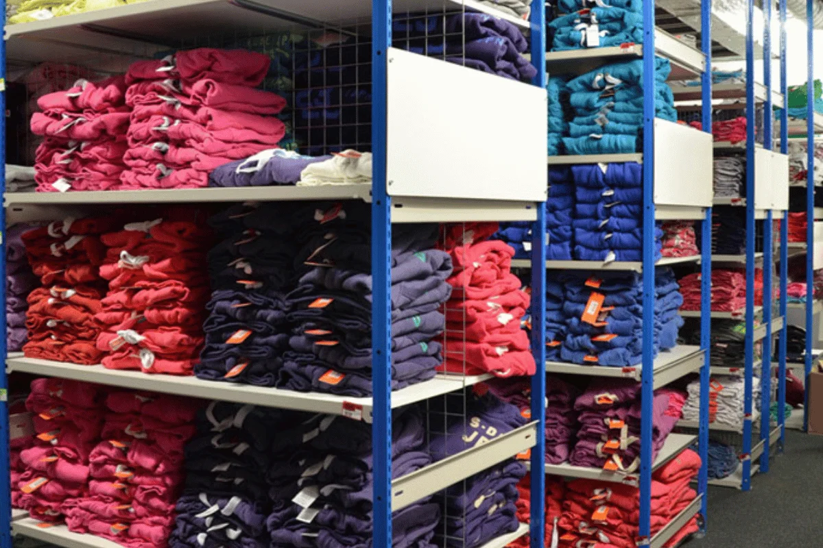 Shelves filled with folded colorful t-shirts in a retail clothing store.