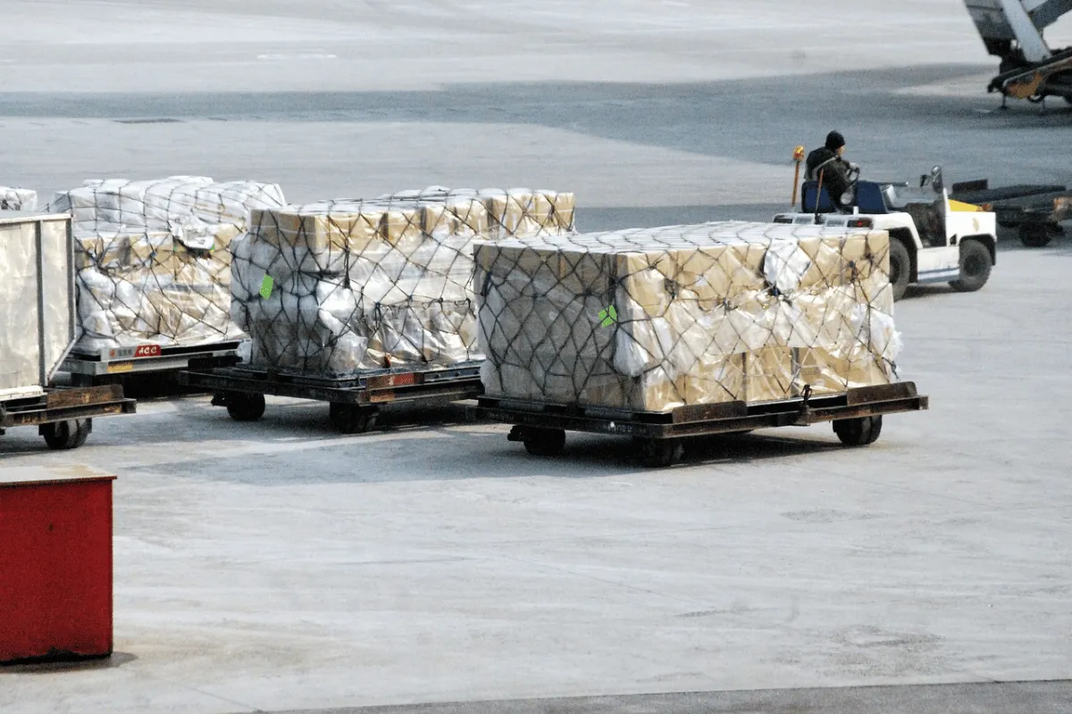 Air Freight Forwarders: Types, Challenges, Solutions & More 10 Bales of freight wrapped and secured with netting at an airport.