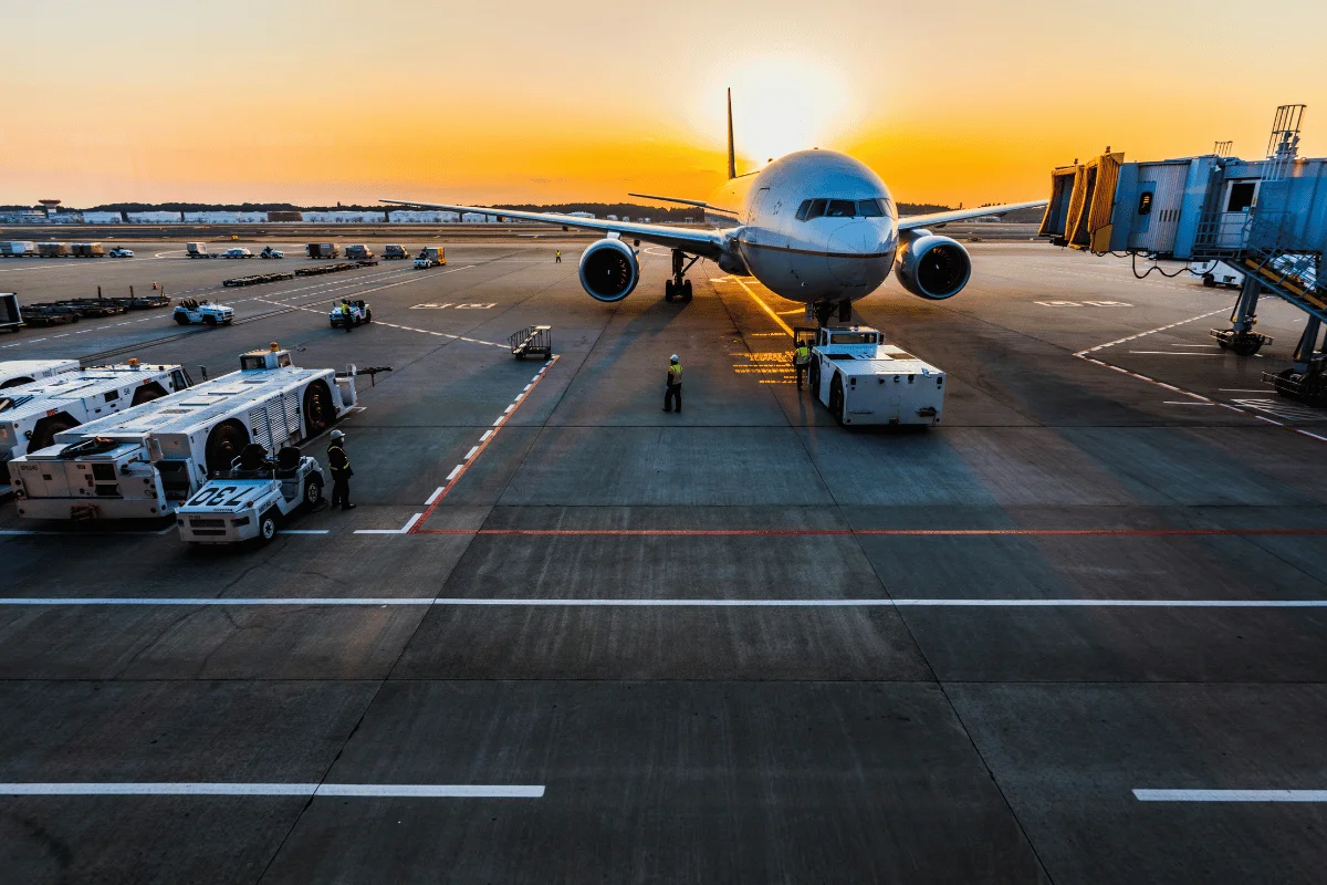 Airport ground crew assisting a large airplane on the tarmac at dusk.