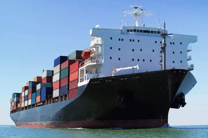 Shipping 10 Cargo ship with stacked containers on clear day at sea.
