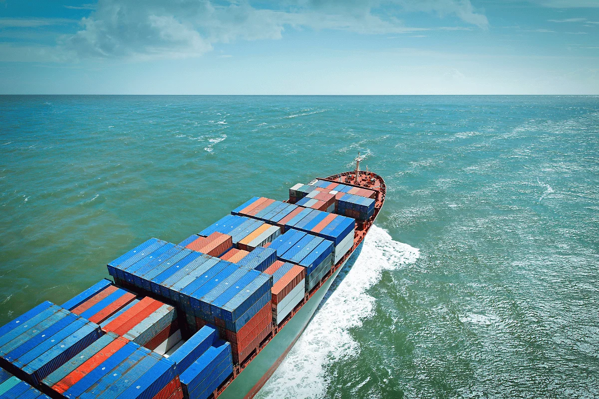 Aerial perspective of a cargo ship loaded with shipping containers on the ocean.