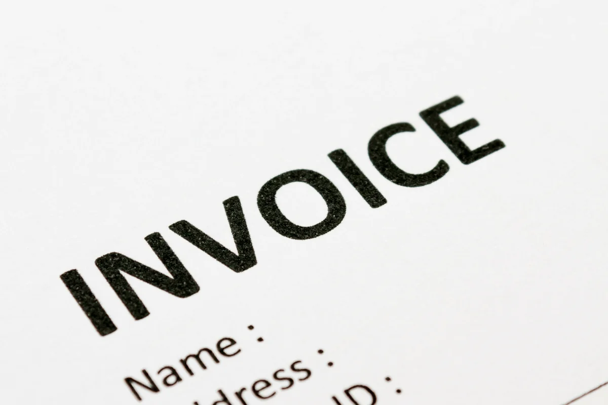 Close-up of a paper with the word "INVOICE" printed at the top.