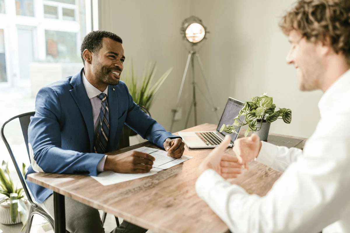 A consultant engaging with a client across a wooden desk.