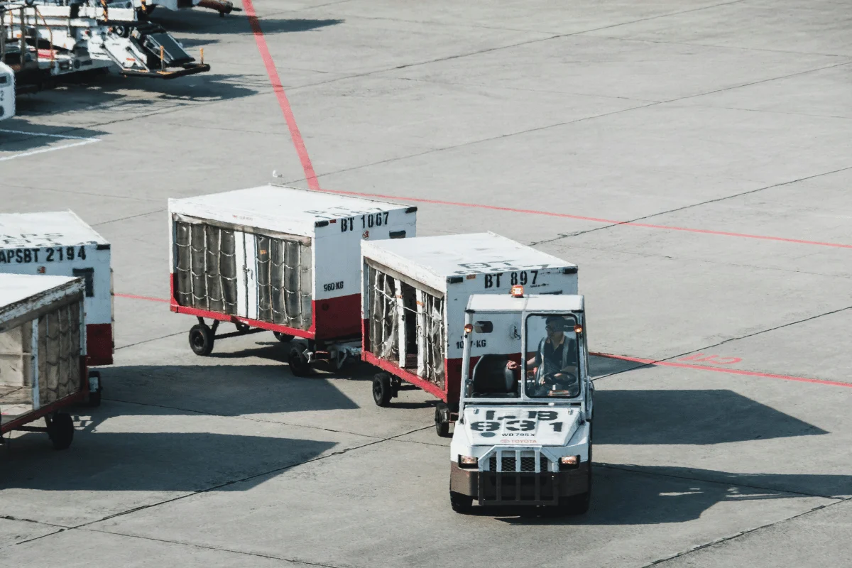 Airport ground crew towing baggage carts.
