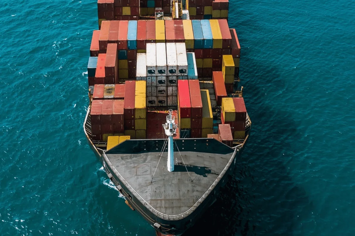 A top-down shot of a cargo vessel with stacked shipping containers in various colors.