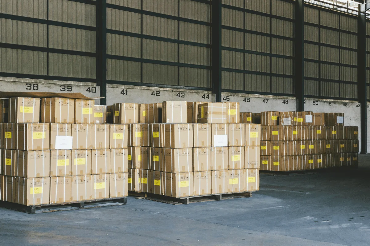 Cardboard boxes stored in a warehouse with numbered bays, prepared for dispatch.