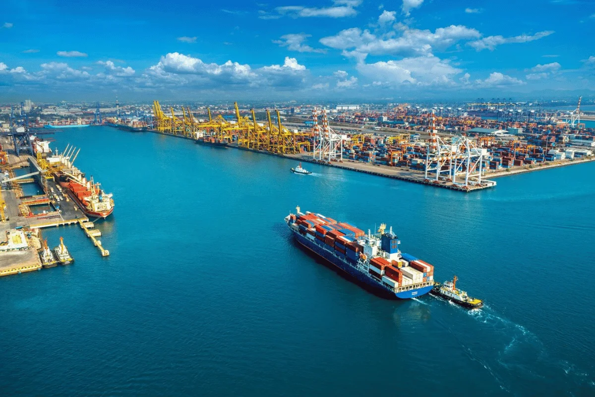Panoramic view of a harbor with container ships and loading cranes.