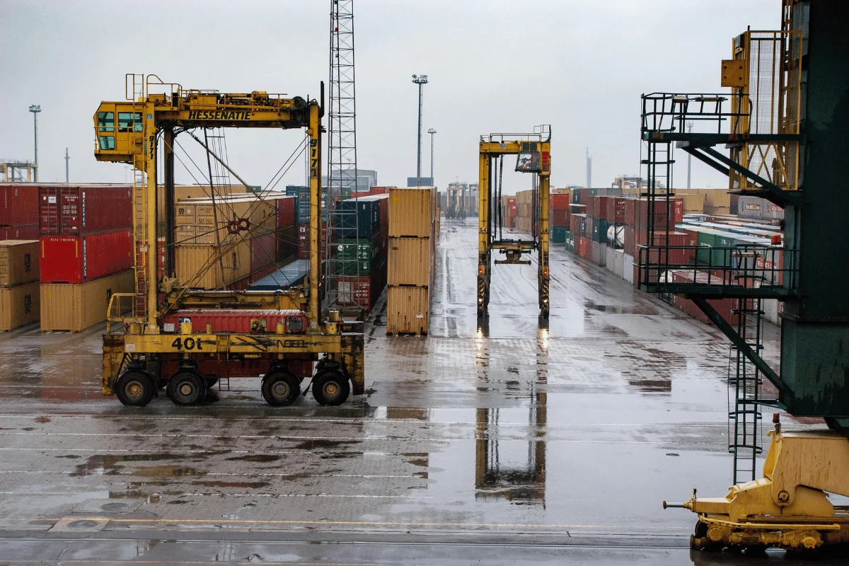 Container yard with heavy-duty cranes and stacked shipping containers.