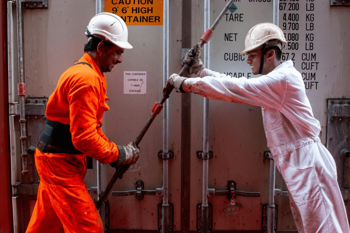 Shipping from Thailand to the USA: Challenges, Solutions & More 7 Two laborers using large tools to lock a container door during loading.