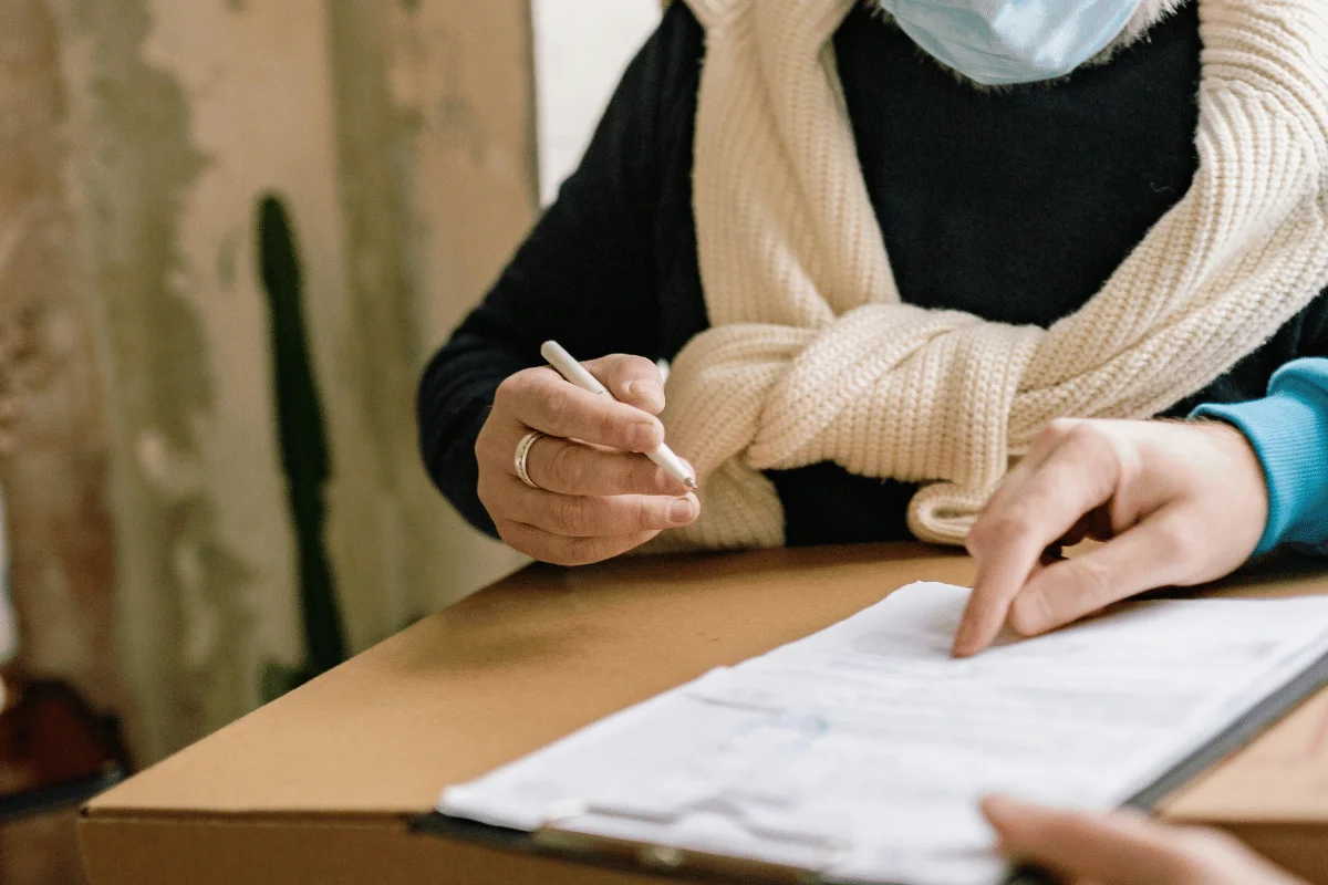 Person signing a delivery receipt on top of a cardboard box.