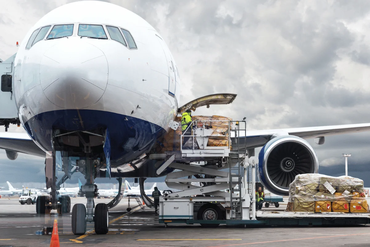 Cargo containers being transported into a commercial aircraft at an airport.