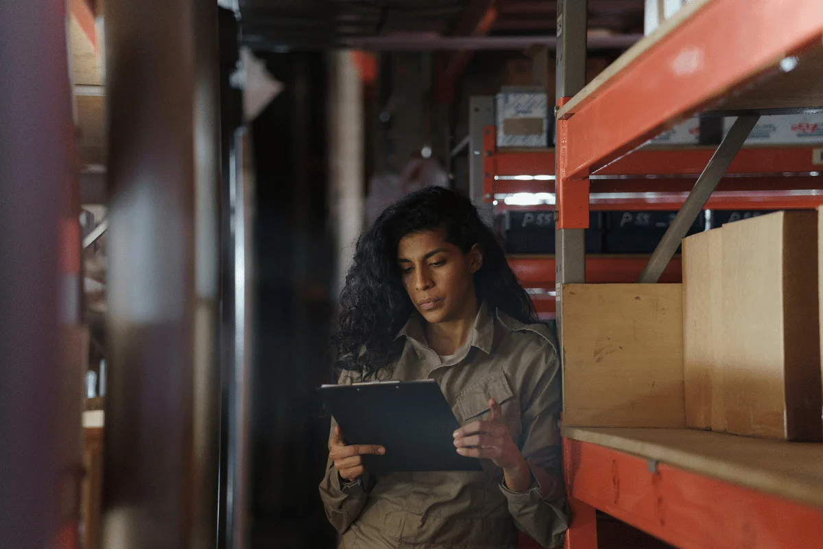 Freight Forwarders in Texas: Significance, Challenges & Tips 9 Worker in a warehouse reviewing inventory on a clipboard.