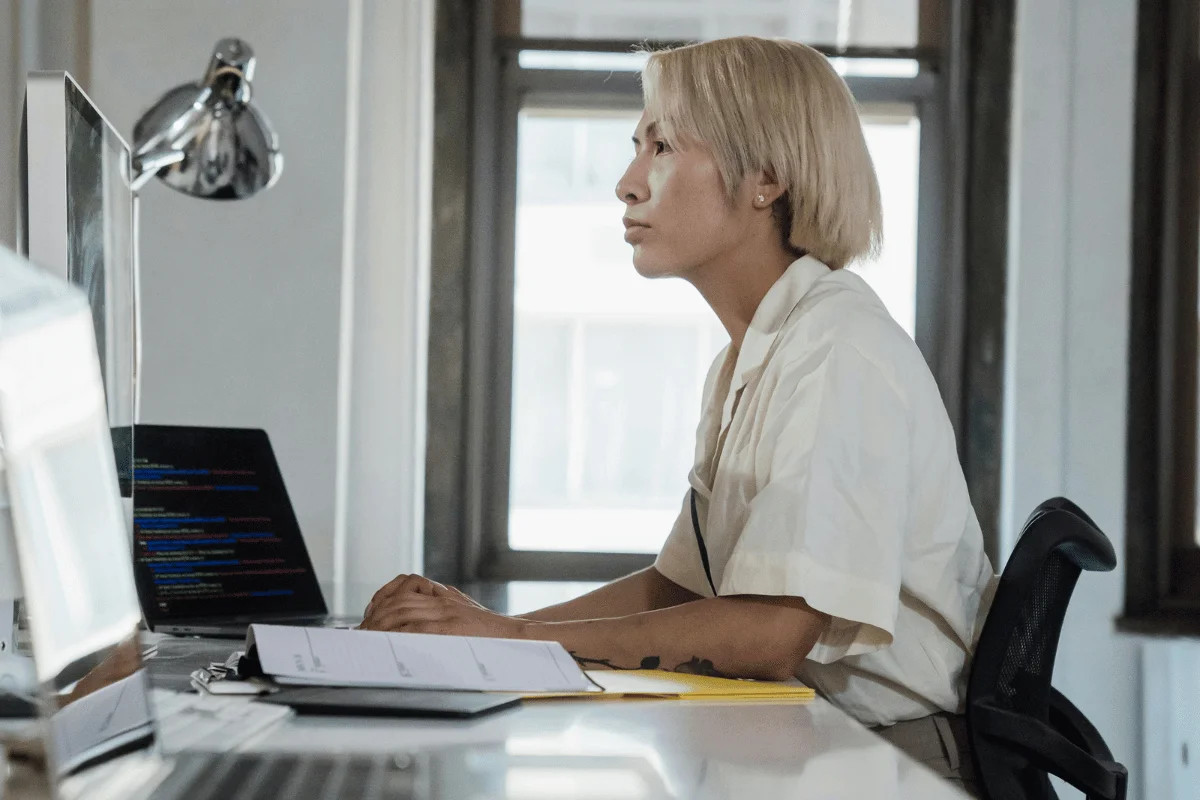 Professional female coder analyzing code on a computer screen.
