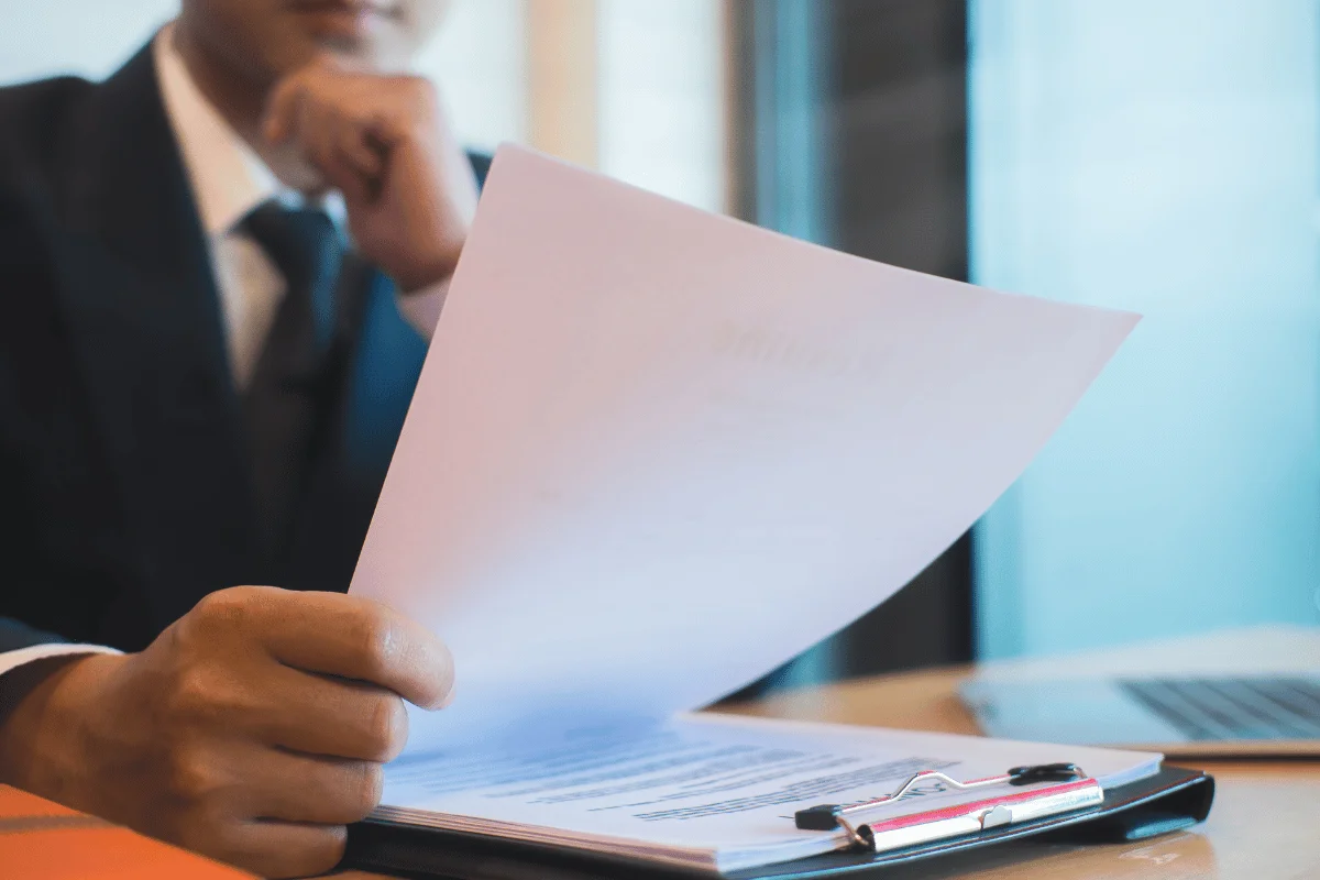 Man in a suit examining a report with a focused expression.