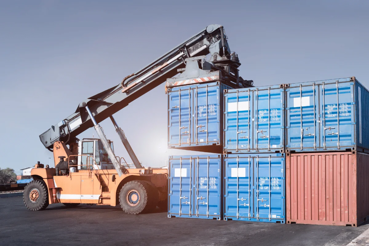 Large forklift positioning cargo containers at a storage site.