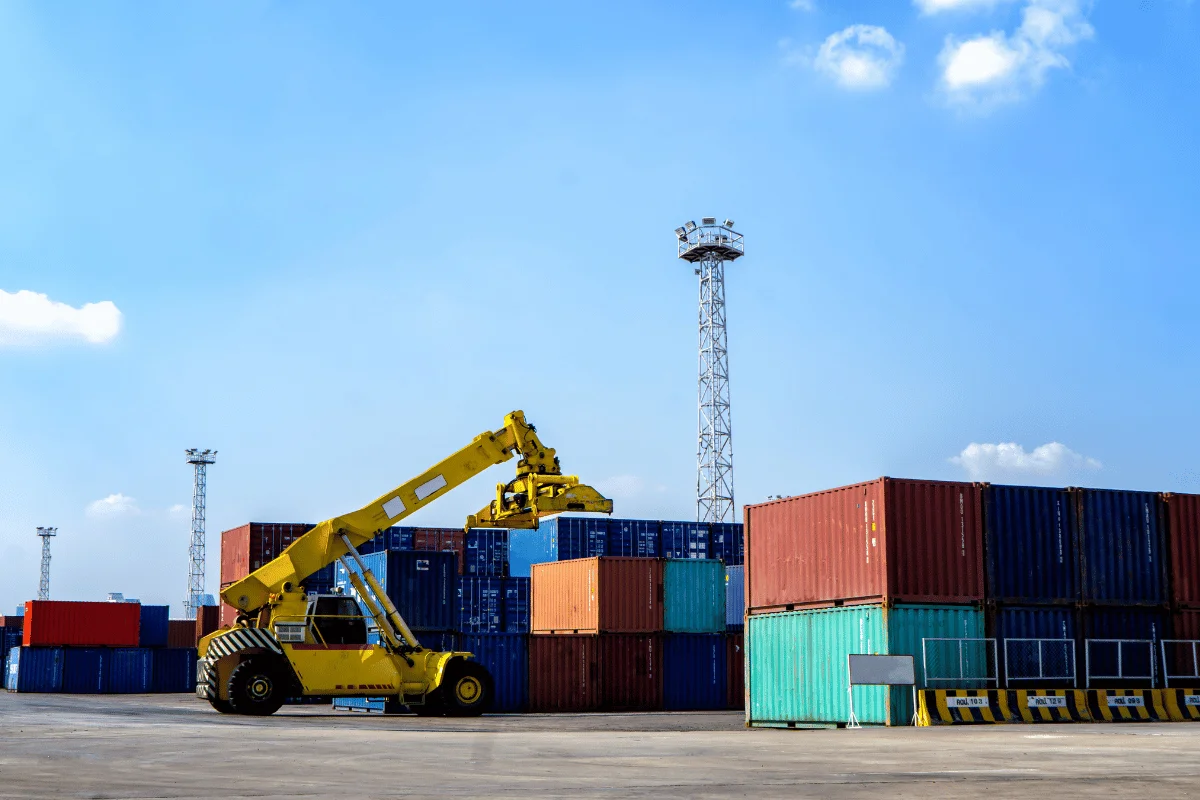 How to Import Toys From China: A Step-by-Step Guide 22 Yellow crane loader lifting shipping containers at a port.