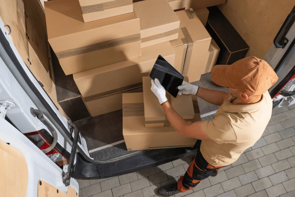 Shipping from Hong Kong to the US: Cost & Solutions Explained 12 Worker using a tablet to check packages in a delivery vehicle.