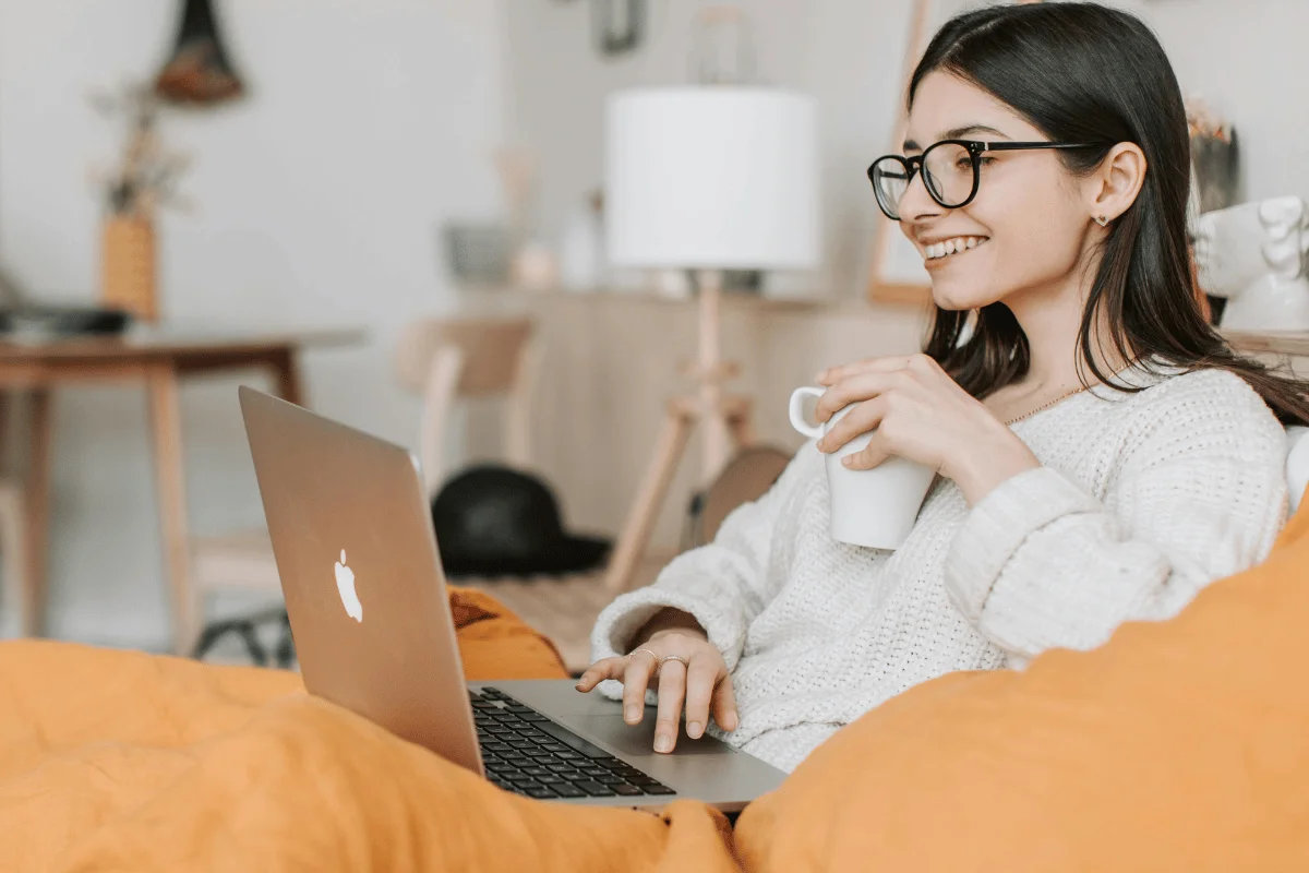 Casual home office setup with a woman working on a MacBook and enjoying coffee.