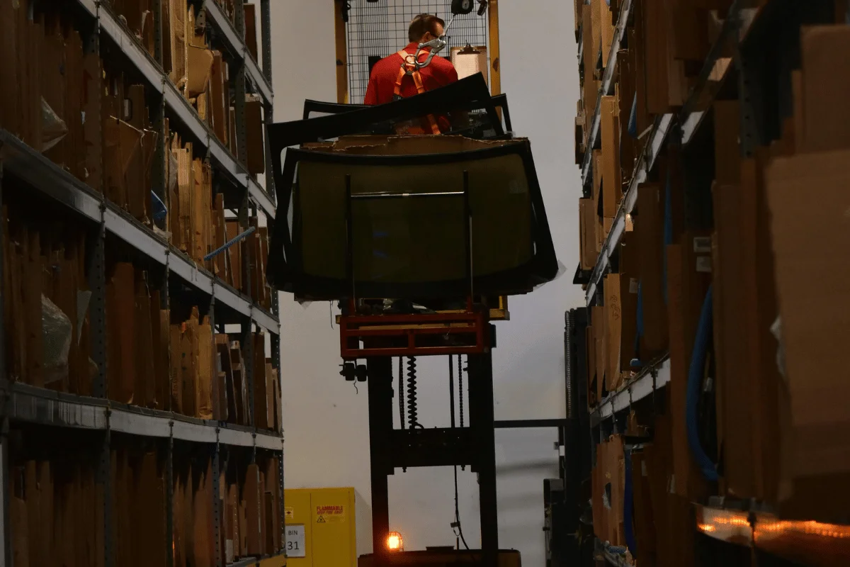 How to Import Clothes from China 22 Employee organizing goods using a forklift in a storage facility.