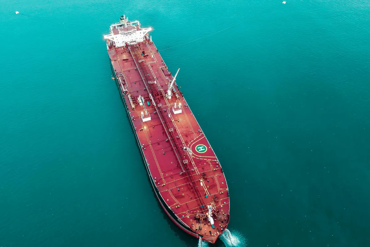 Red cargo vessel with a helipad navigating through the ocean.