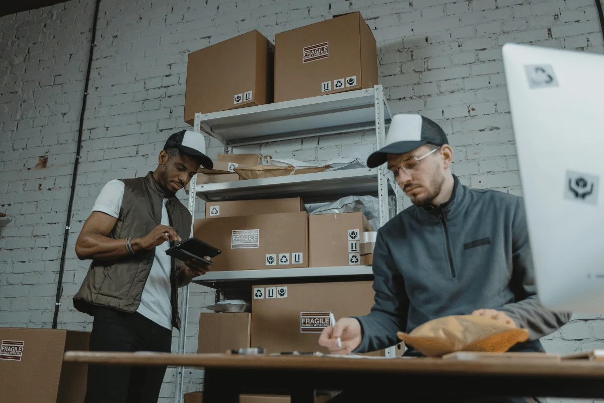 Employees preparing and managing fragile packages for shipping in a warehouse.