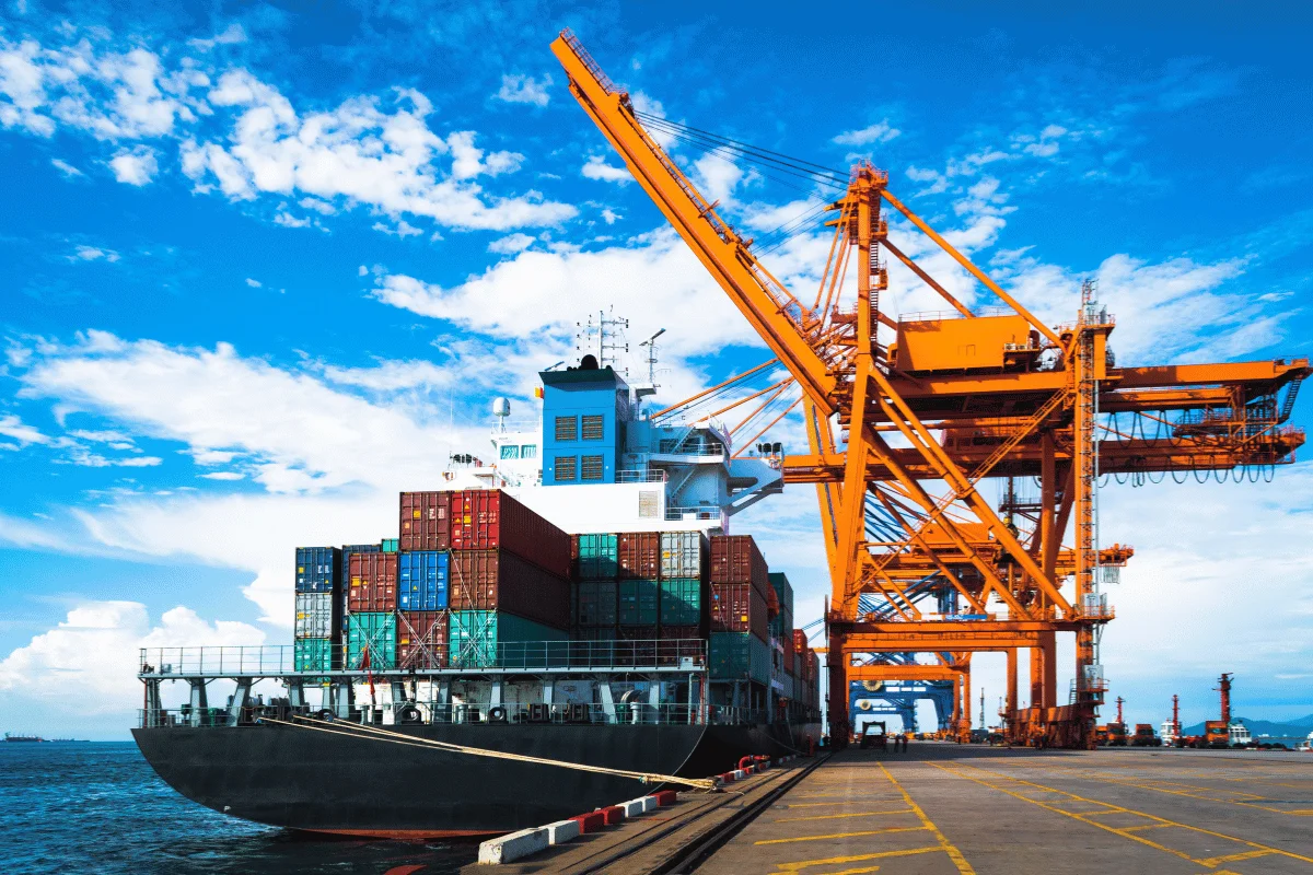Shipping vessel at a harbor with stacked containers, illustrating global trade and maritime logistics.