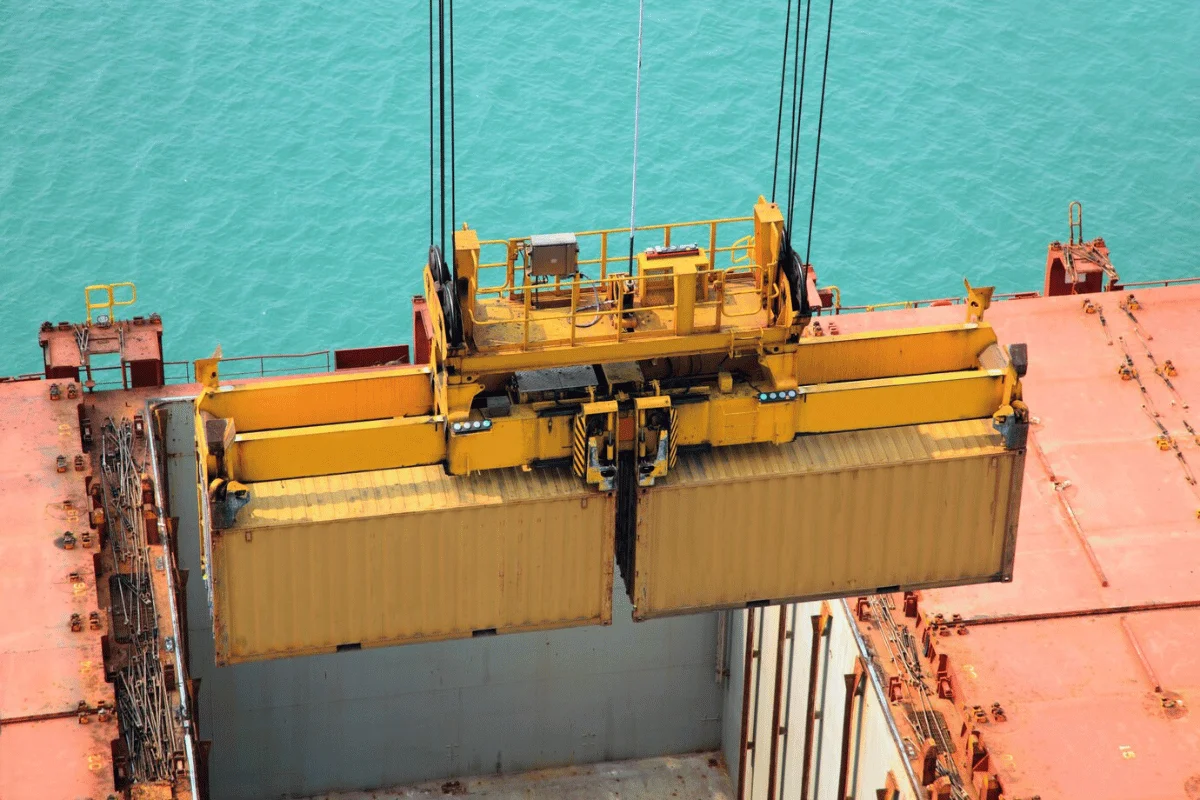 Aerial view of a crane lifting a container on a cargo vessel.