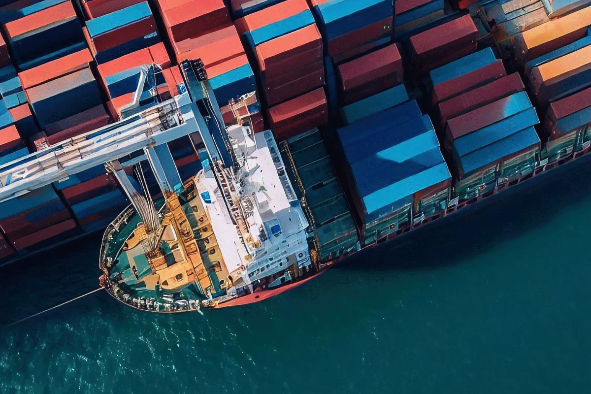 Cargo ship with an array of stacked containers, captured from an aerial perspective.