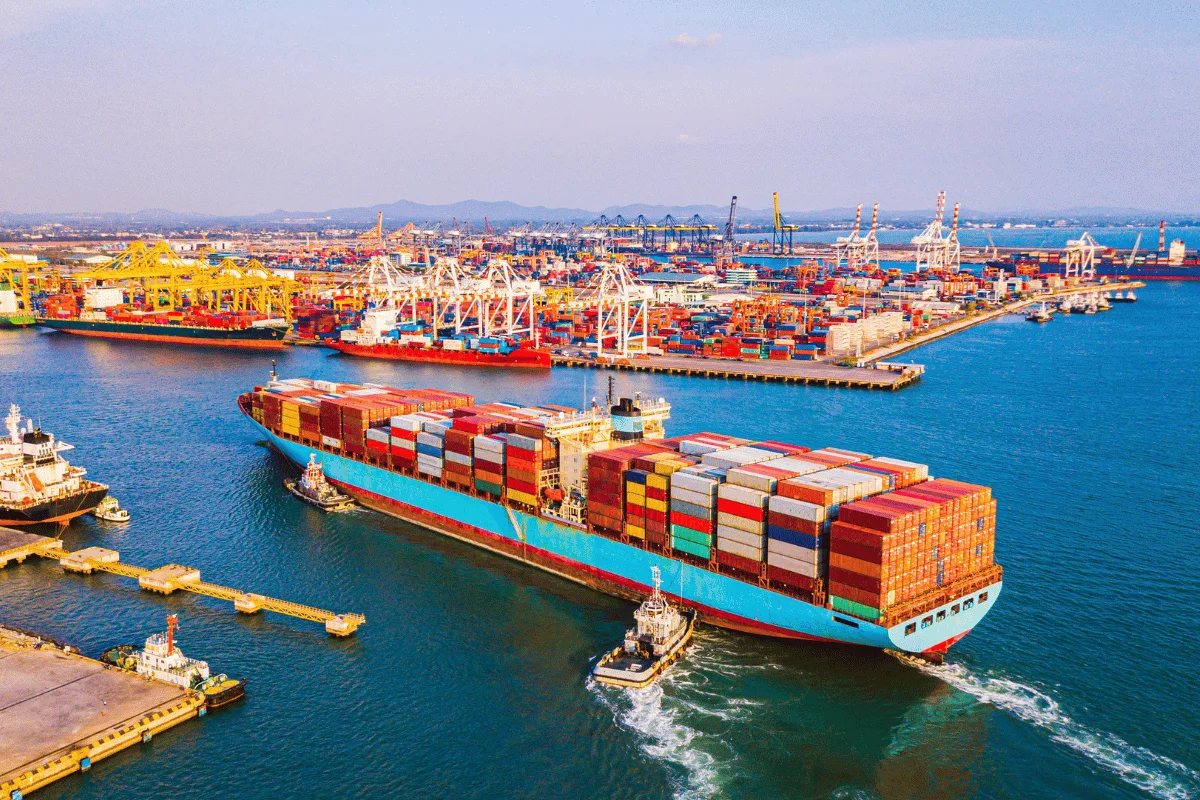 Freight Forwarders in Texas: Significance, Challenges & Tips 12 Container ship arriving at a bustling port with colorful cargo and cranes.