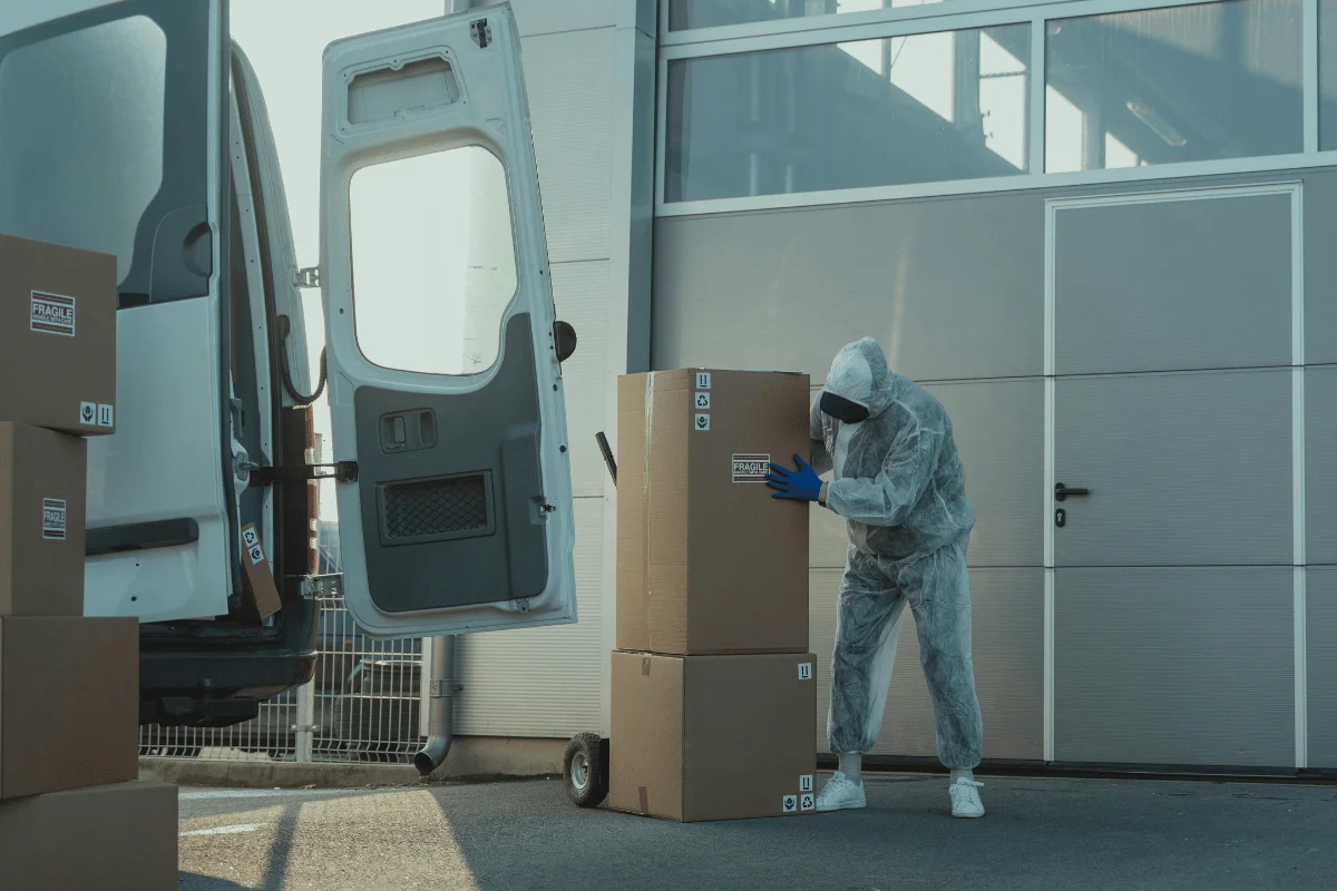 Delivery worker in protective gear handling fragile packages near a van.