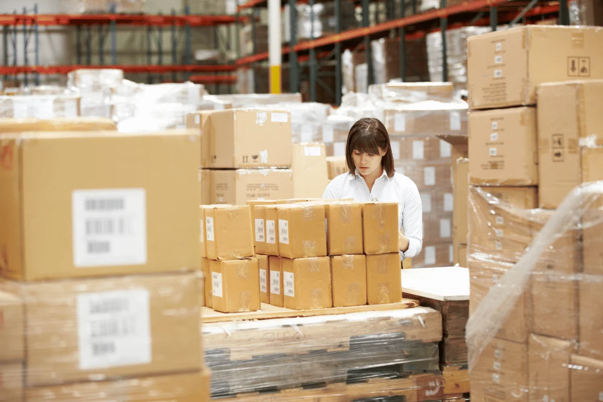 Warehouse staff sorting and stacking packages on pallets.