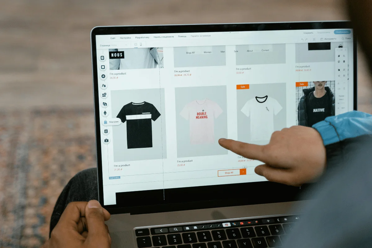 Person navigating through an e-commerce website on a laptop, pointing at a product.