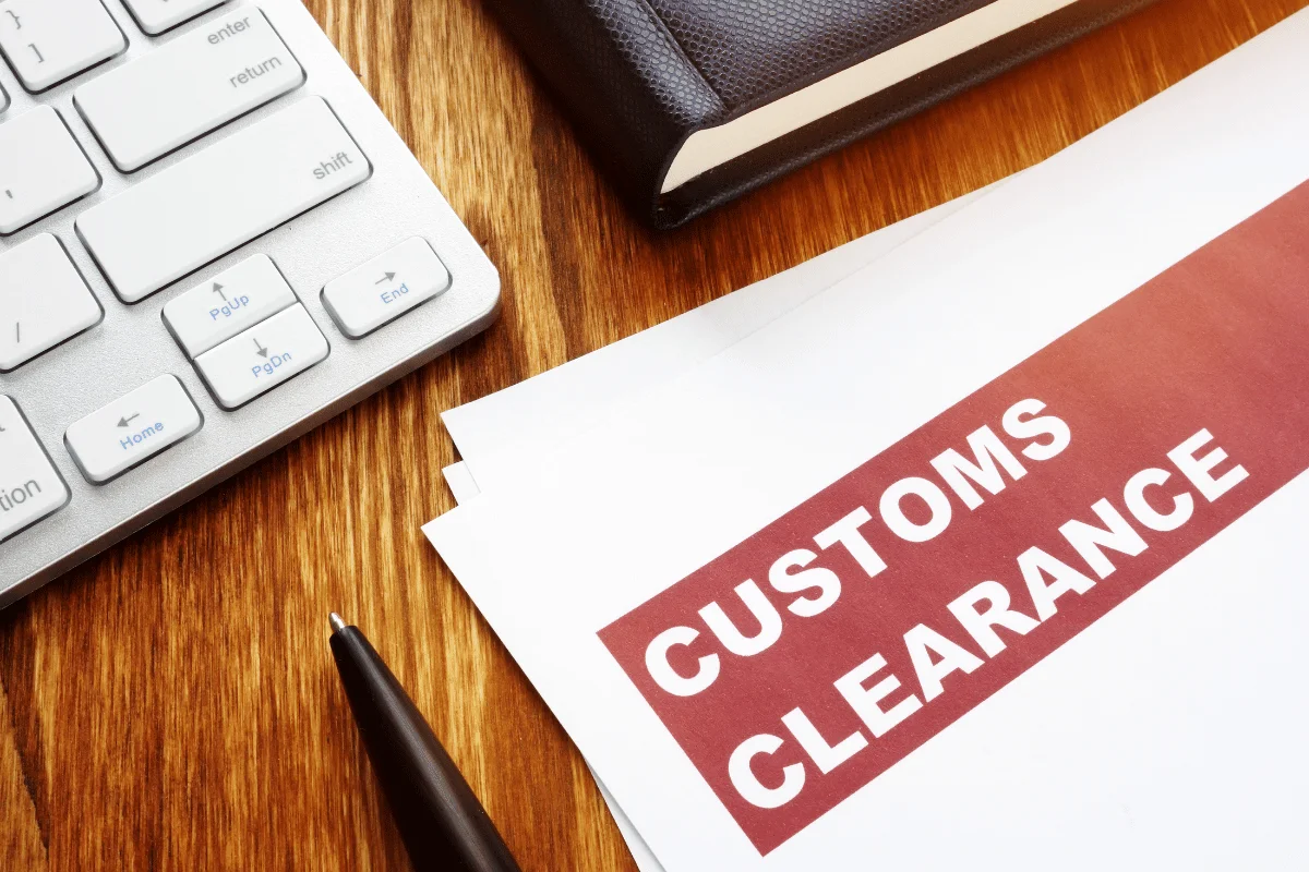 Customs clearance document on a wooden desk with a keyboard and pen.