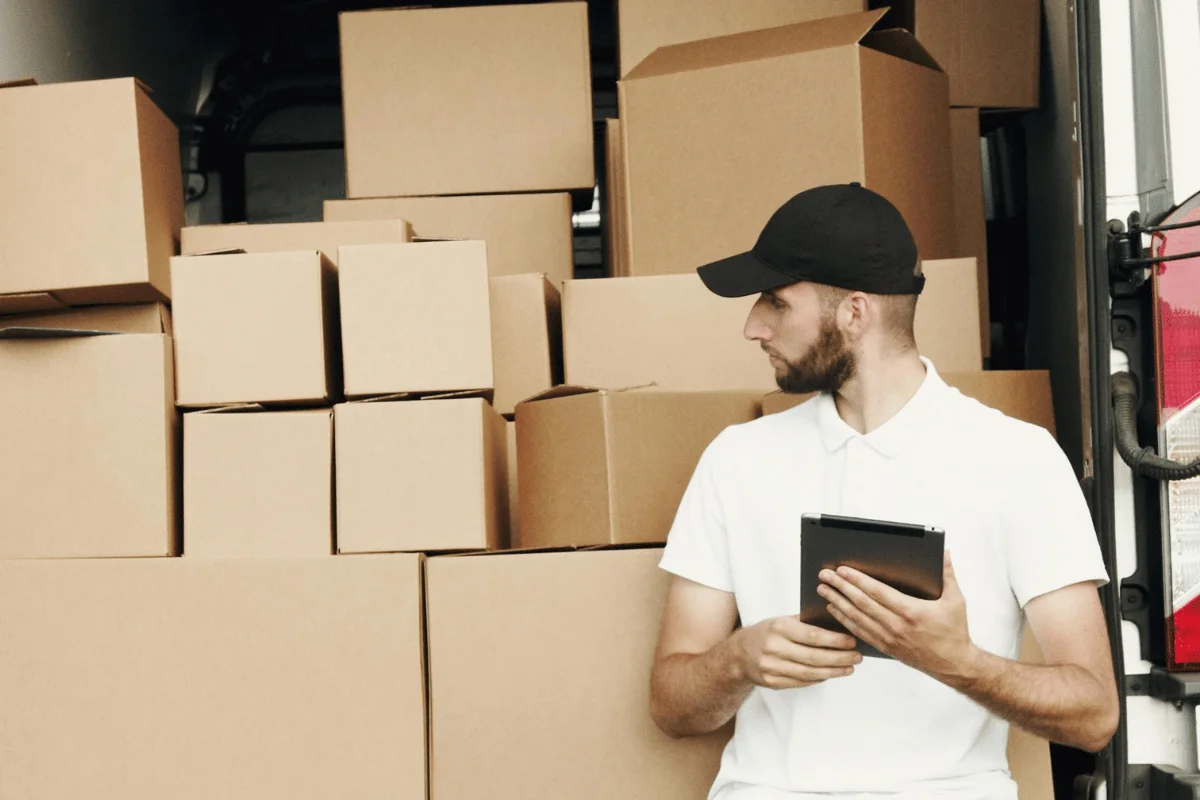 Courier checking packages with a tablet near a delivery van.
