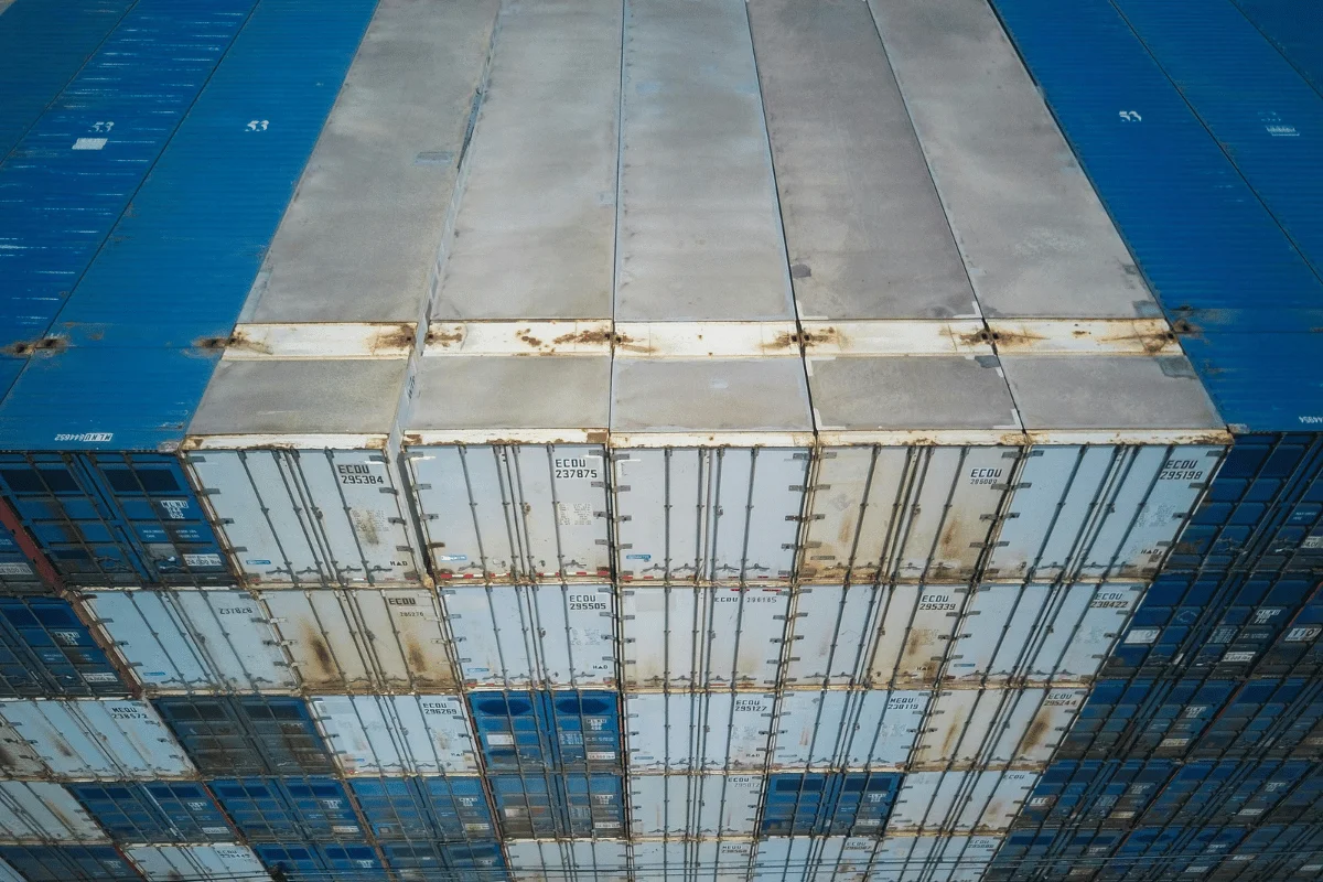 Freight Forwarder vs. Common Carrier: A Guide for Importers 12 Stacked shipping containers on a cargo vessel, showing wear and rust.