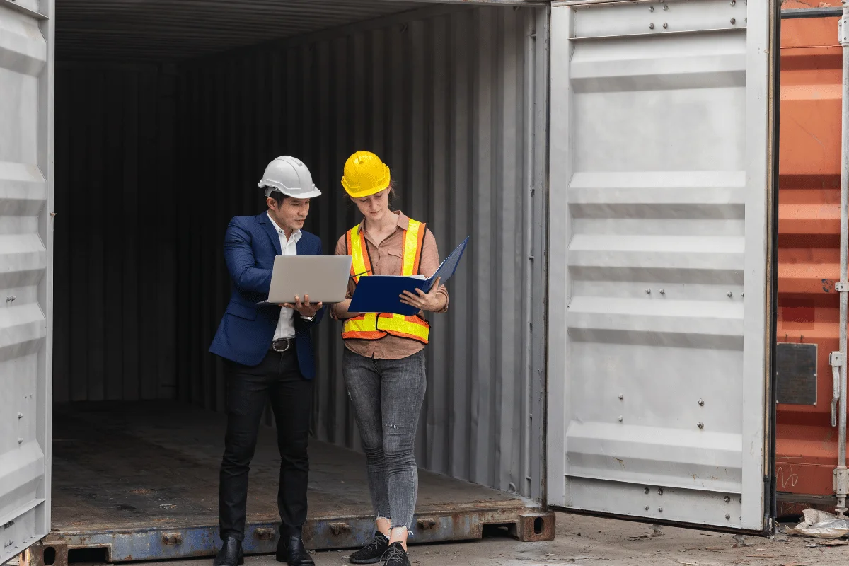 Engineer and supervisor discussing project details in front of an open container.