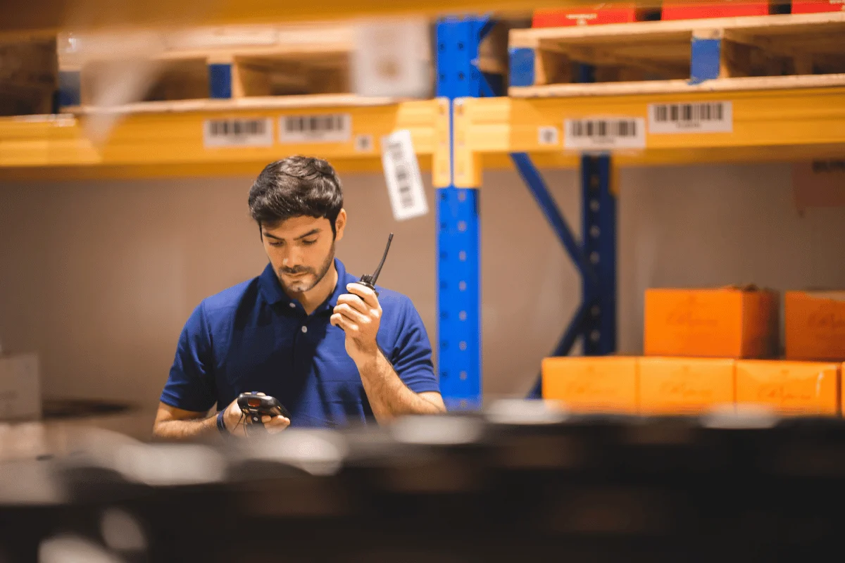 Worker in a warehouse using communication equipment for logistics.