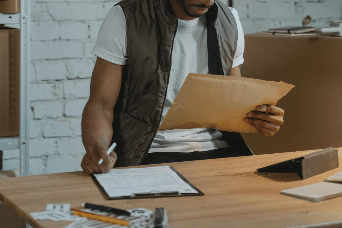 Man reviewing documents at a table with a clipboard and phone nearby.