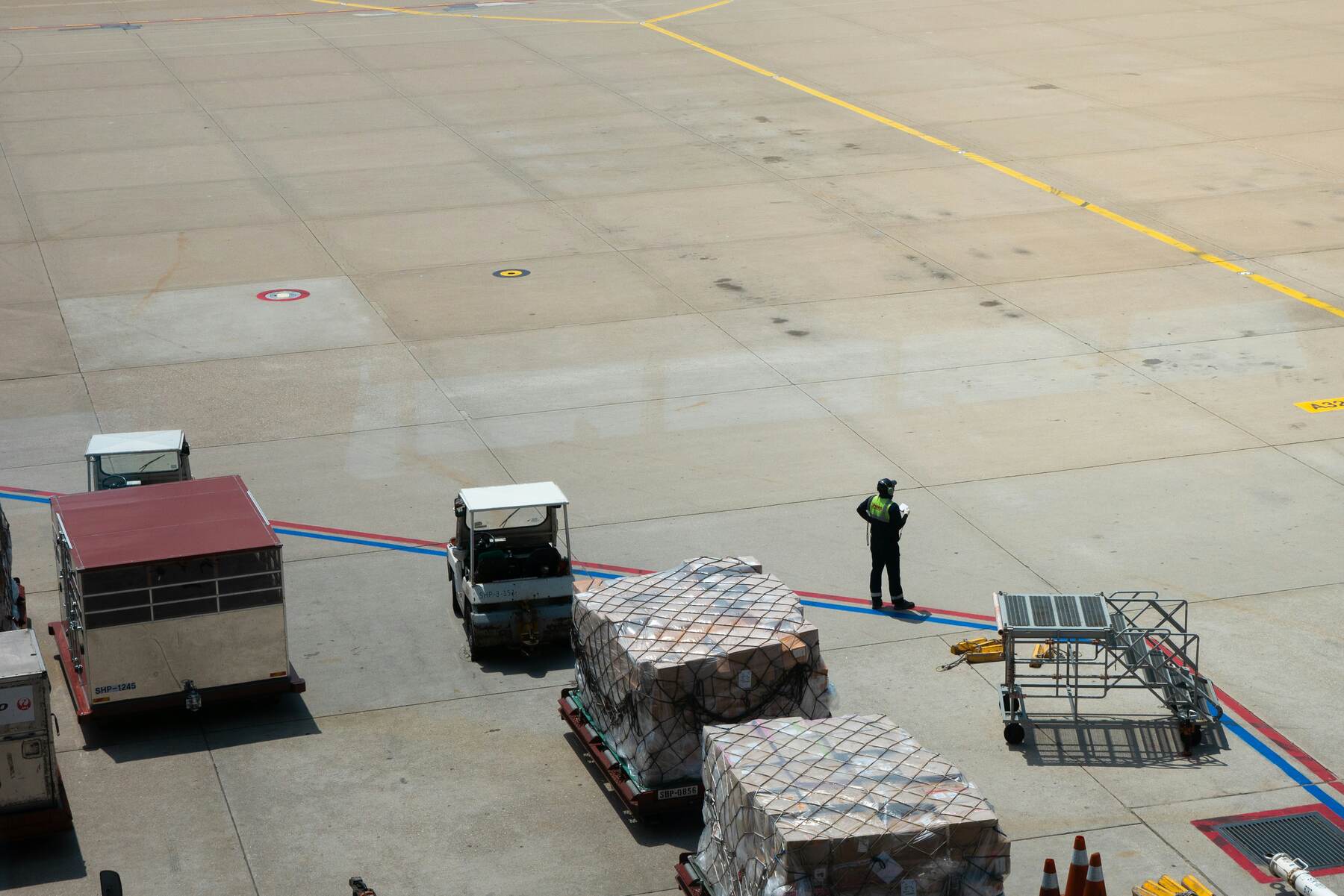 Airport corridor nearly empty with a couple of cargo-loaded stacks and a man waiting
