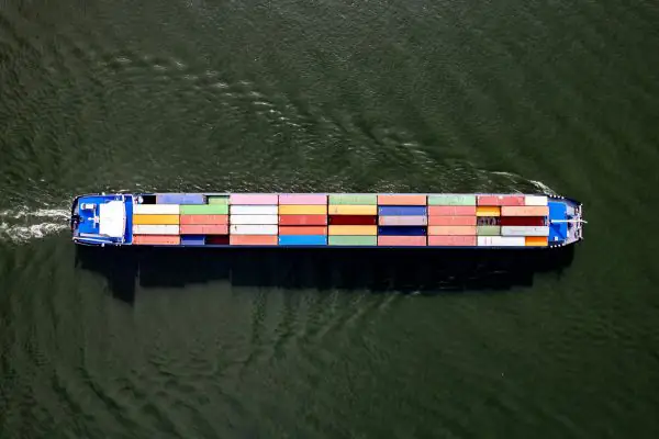 Cargo vessel with shipping containers sailing at the sea.